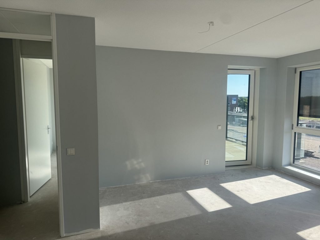 Nieuw appartement met lichtgrijs gesausde wanden en een balkondeur