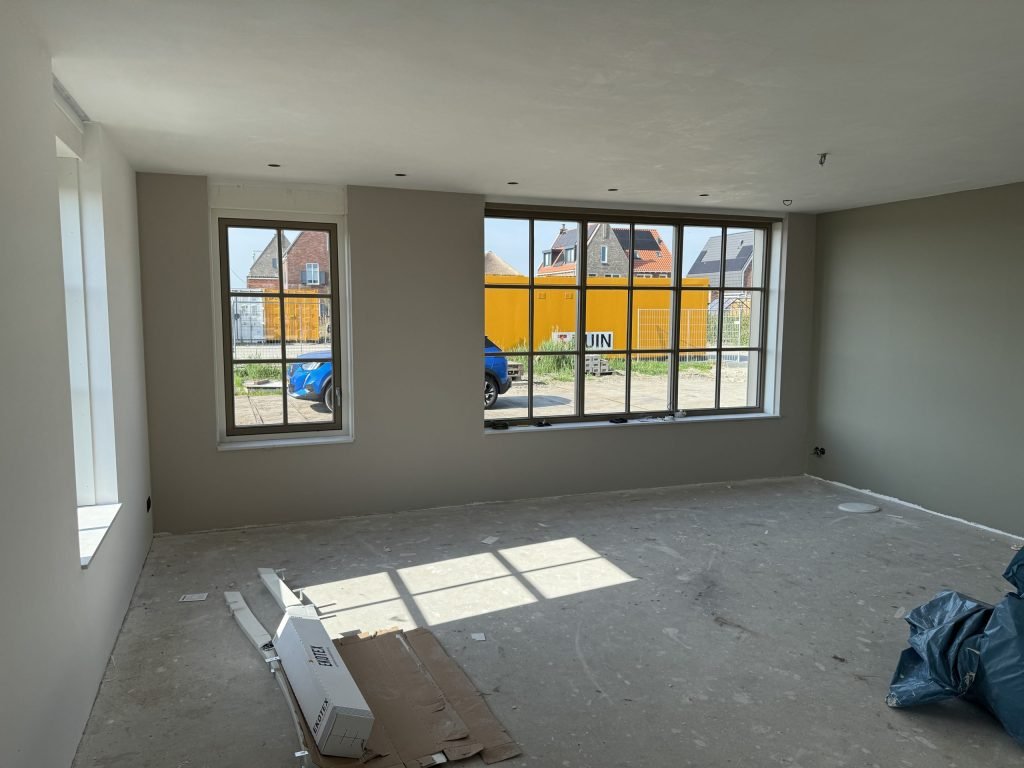Nieuwbouwkamer met wanden in een warme grijstint en grote roedenramen