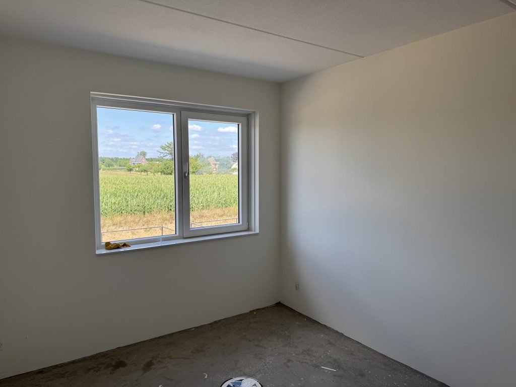 Lege slaapkamer met gladde lichte wanden en uitzicht over een veld