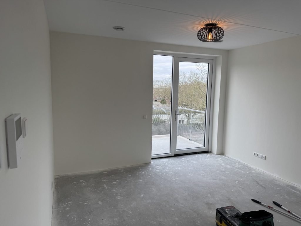 Lege nieuwbouwkamer met balkondeuren, kort na de oplevering